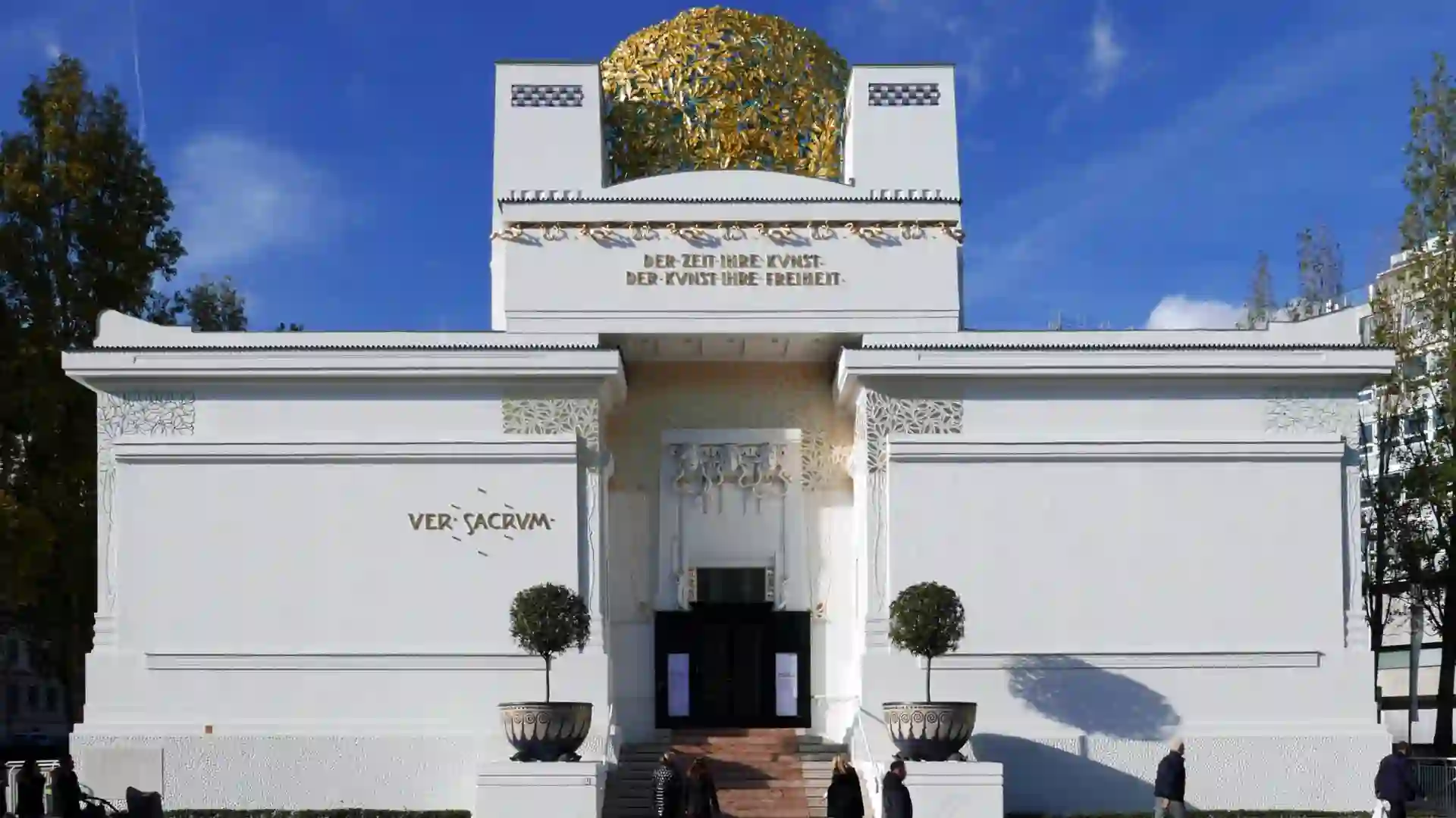 A white building topped with a gold dome, showcasing a classic architectural design against a clear sky