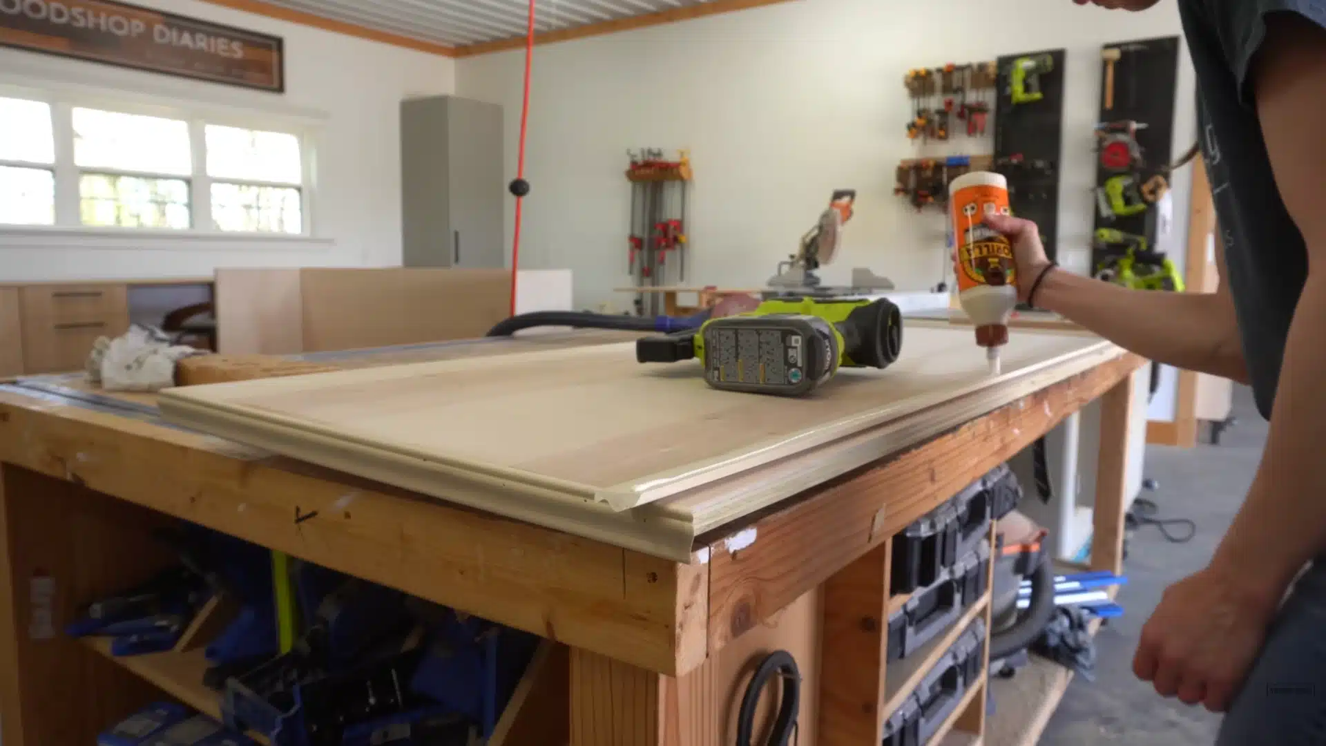 Applying wood glue along panel edges while preparing top section for Murphy bed cabinet construction