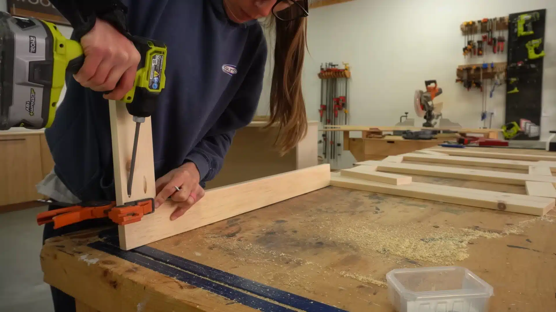 Attaching wooden frame pieces with drill and clamp to build faux door front for Murphy bed structure