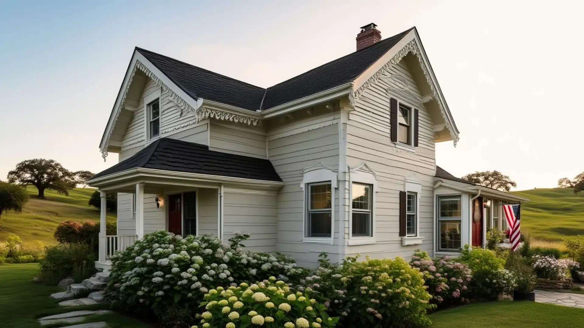 Cottage-style exterior window trim on a white farmhouse with decorative gable accents, shutters, and hydrangea landscaping