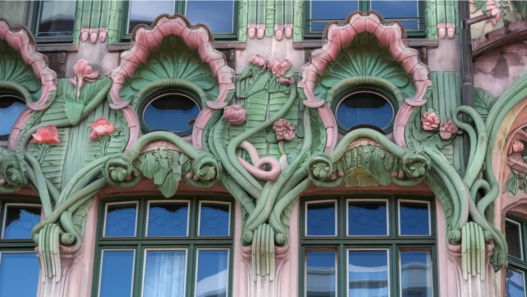 Ornate building facade adorned with vibrant green and pink flowers, showcasing intricate architectural details