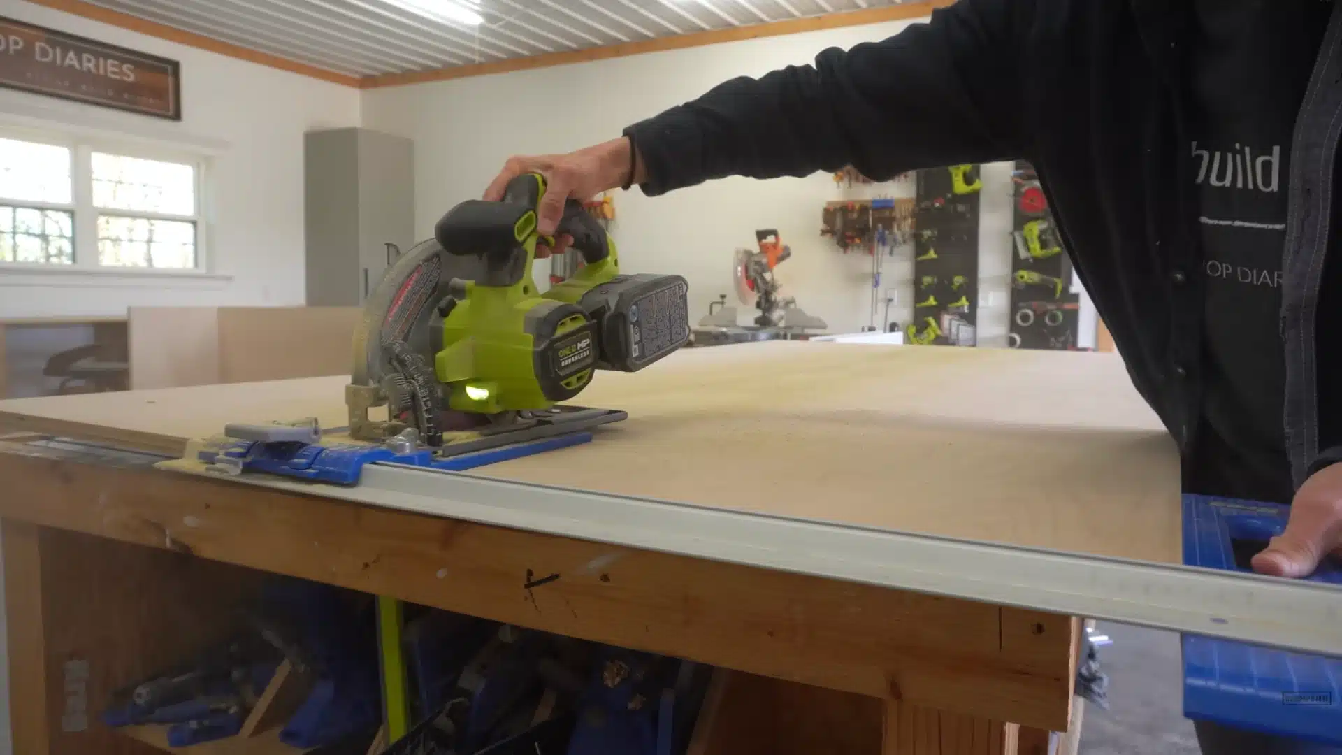 Person cutting plywood sheet using circular saw on workbench in workshop for Murphy bed cabinet panels
