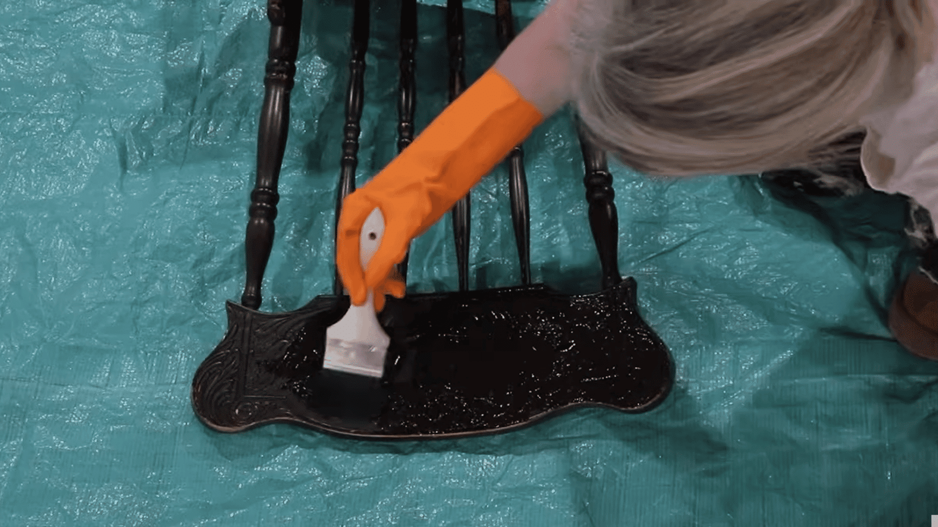 Applying a thick coat of paint stripper on detailed wooden furniture with a brush